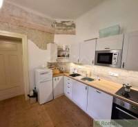 A kitchen in a family house with white cabinets and a wood-patterned floor.