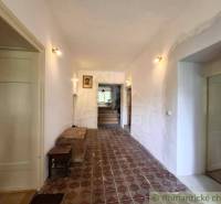 A hallway in a family house with patterned tiles, bright, wooden doors, paintings on the wall.