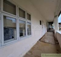 A veranda at a family house in Mužla with window blinds and a garden in the background.