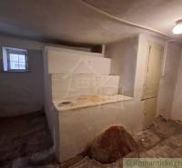 Interior of a family house with an old stove, a window, and a light on the ceiling.