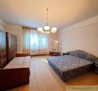 A bedroom in a family house with a double bed, a single bed, and a floor with a wooden decor.