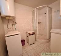 A bathroom in a family house with a shower and appliances, tiled.