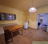 A kitchen in a family house with furniture and a light fixture, flooring with a wooden decor.