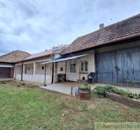 A family house in Mužla with a traditional facade, a veranda, and a lush garden.