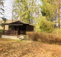 A cottage surrounded by forest on recreational land in Holčíkovce during autumn.