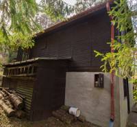 A wooden cottage surrounded by greenery on recreational land in Holčíkovce.