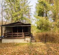 A wooden cabin surrounded by trees on recreational land in Holčíkovce.