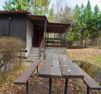 A cottage with a terrace and a table on Recreational Land in Holčíkovce, surrounded by forest.