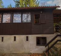 A wooden cottage on recreational land in Holčíkovce surrounded by greenery and trees.