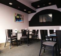 Gastro premises with black chairs, art on the wall, and a television.