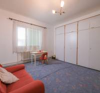 The family house includes a living room with carpeted flooring, an orange couch, and a white table.