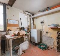 Basement of a family house with a boiler, shelves, hose, and work table.