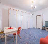 A living room in a family house with a blue carpet, a sofa bed, and storage cabinets.