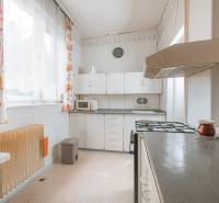 A kitchen in a family house with white cabinets, a stove, and colorful curtains.