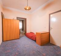 A room in a family house with a blue carpet, wooden furniture, and a bed.
