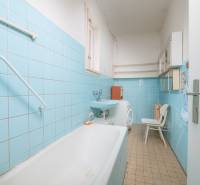 Bathroom with blue tiles, sink, bathtub, washing machine, and shelves in a family house.