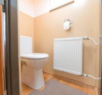 A toilet in a family house with a radiator and a floor with a wooden decor.