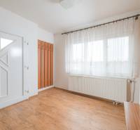 The interior of a family house with white walls, windows, and a floor with a wooden decor.