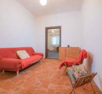 Living room with a red sofa, armchair, magazines, and wood-patterned flooring in a family house.