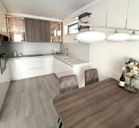 A kitchen in a 2-room apartment with a wooden decor floor, bright interior, and a dining table.