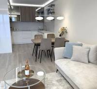 Living room in a two-room apartment with a wooden decor floor, sofa, and dining table.