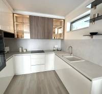 A kitchen in a 2-room apartment with white cabinets and a wood-patterned floor.
