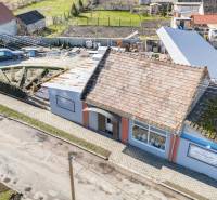 Commercial premises in Okoč with a traditional roof, walkway, and garden.