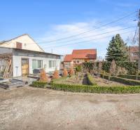 Commercial premises in Okoč with garden landscaping, surrounded by trees and shrubs.