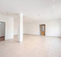 Spacious commercial spaces with white walls, tiles, and illuminated ceiling lights.