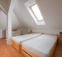 Attic bedroom with two single beds and a wooden decor floor in a 2-room apartment.