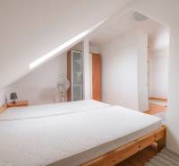 Attic bedroom in a 2-room apartment with a bed and a wardrobe, carpet on the floor.