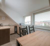 A kitchen in a 2-room apartment with a wooden decor floor, large windows with a view.
