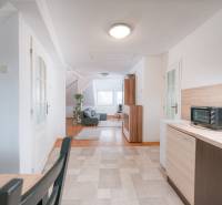 A bright kitchen connected to the living room with a wooden decor floor in a 2-room apartment.