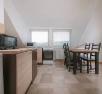 A kitchen in a 2-room apartment with a dining table, appliances, and tiles.