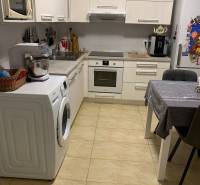 A kitchen in a 2-room apartment with white cabinets and ceramic flooring.