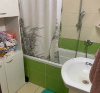 A bathroom with a bathtub and colorful tiles in a 2-room apartment.