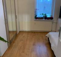 A room in a 2-room apartment with a wooden decor floor and a wardrobe with a mirror.