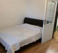 Bedroom in a 2-room apartment with a wood-patterned floor and a large bed.