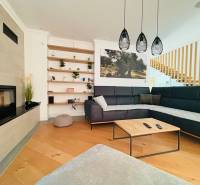 Interior of a villa with a wooden decor floor, a comfortable sofa, and a built-in fireplace.