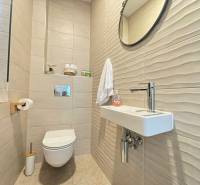 Bathroom in a villa with tiled walls, a mirror, and a simple sink.