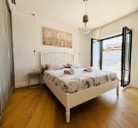 A bright bedroom in a villa with a bed, balcony, and wooden decor flooring.