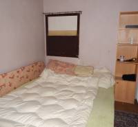 A room with a bed, a shelf, and a radiator, suitable for renovation of catering spaces.