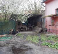 Exterior in dining spaces in Búč with an old oven and spring vegetation.