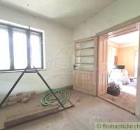 A room in a cottage with light from the window, open doors, and construction mess.