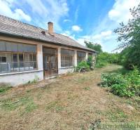 An old house in the gardens of Kamenný Most surrounded by lush greenery and trees.