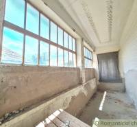 A cottage in Kamenný Most with a long veranda and large windows, in need of renovation.