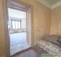 A room in a cottage with old furniture and a window, waiting for renovation.