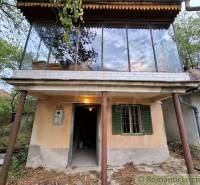 A cottage in Kamenín with a glass terrace, surrounded by nature and trees.