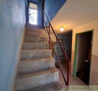 Concrete stairs in the interior of a cottage with blue walls and metal railing.
