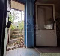 The doors leading from the cottage to the garden with leaves and concrete steps in Kamenín.